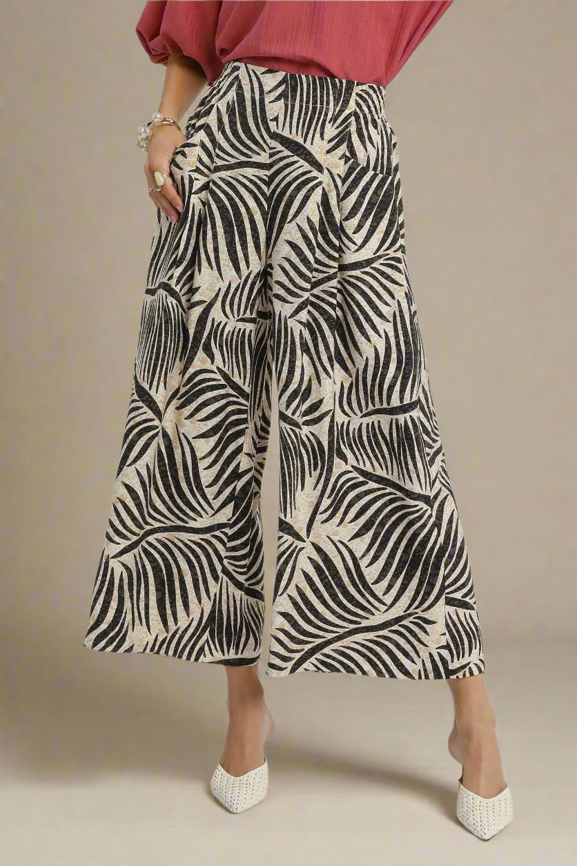 Person wearing wide-leg pants with a black and beige pattern on a white background