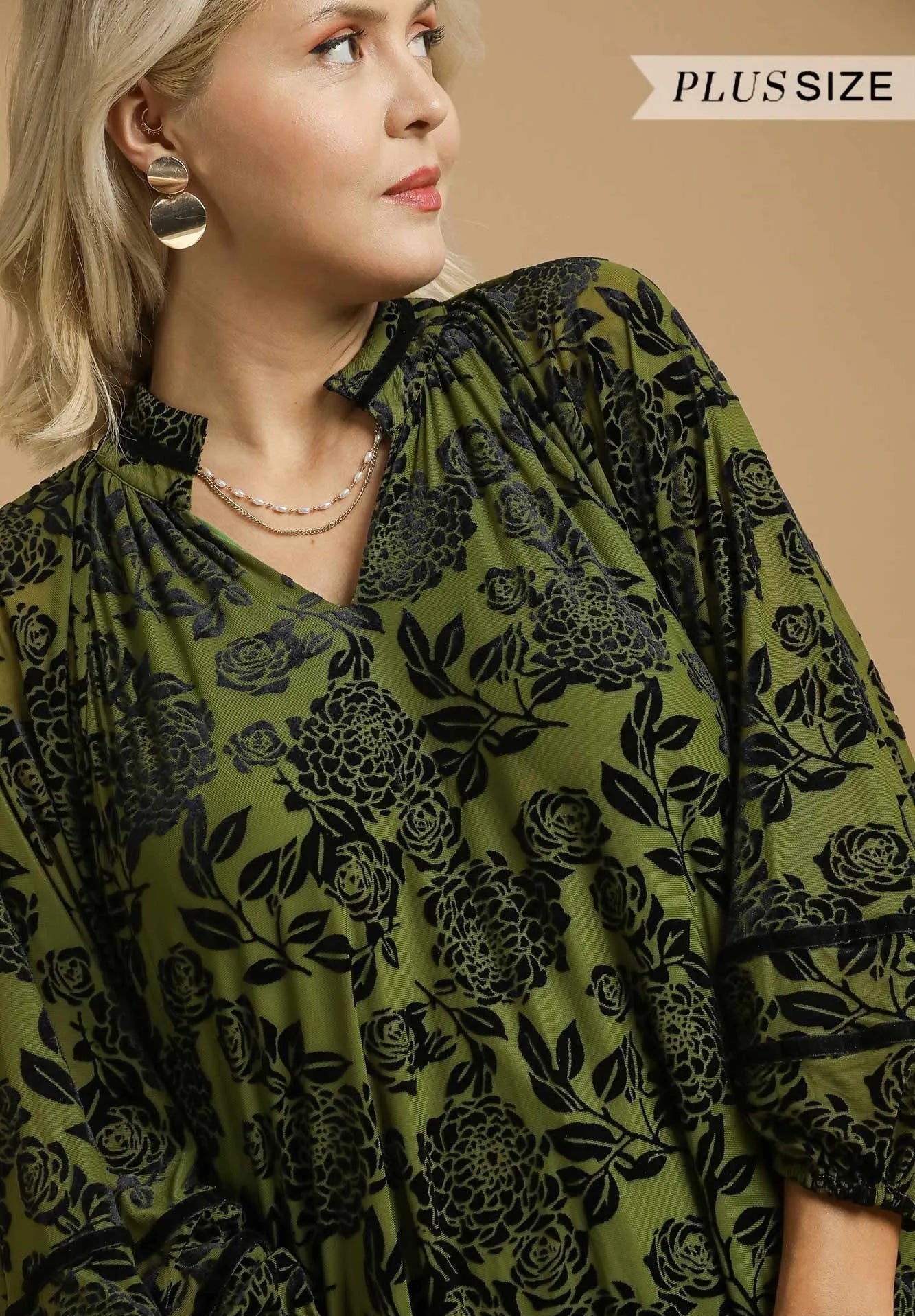 Woman wearing a green floral blouse with 'Plus Size' text above her.