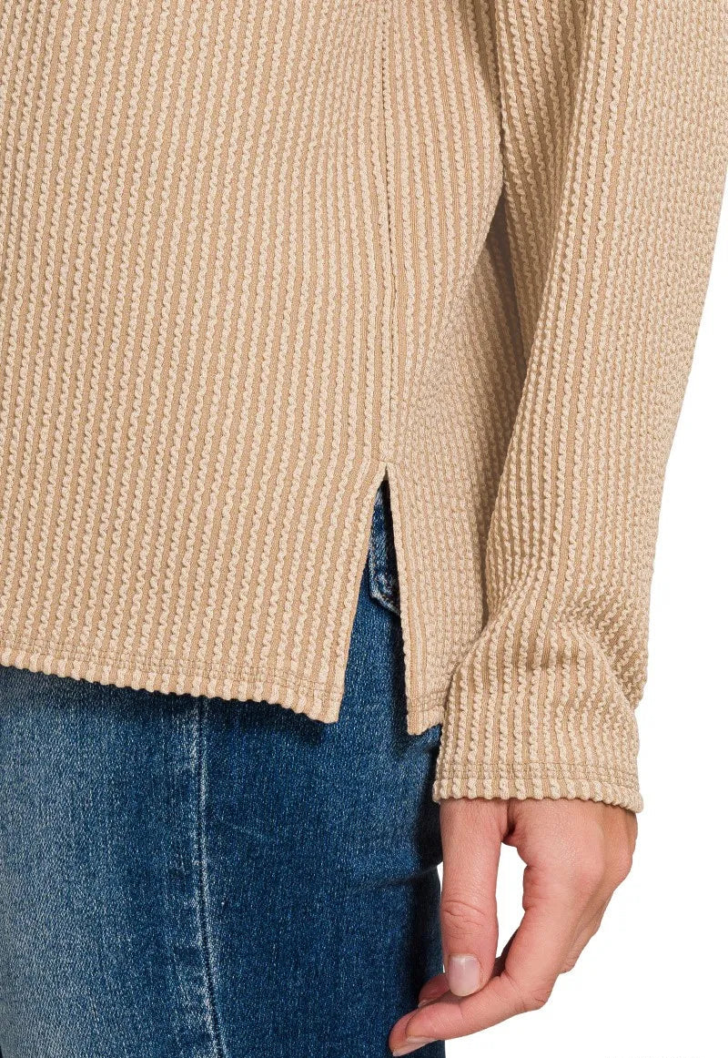 Beige sweater with a slight slouchy fit worn over blue jeans on a white background.