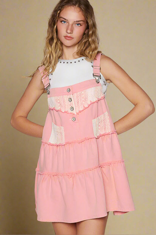 Woman wearing a pink dress with lace details on a plain background