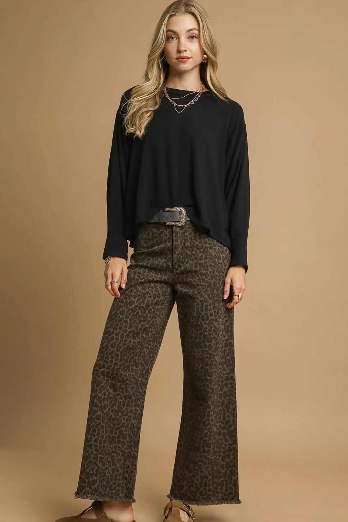 Woman wearing a black top and patterned pants on a beige background