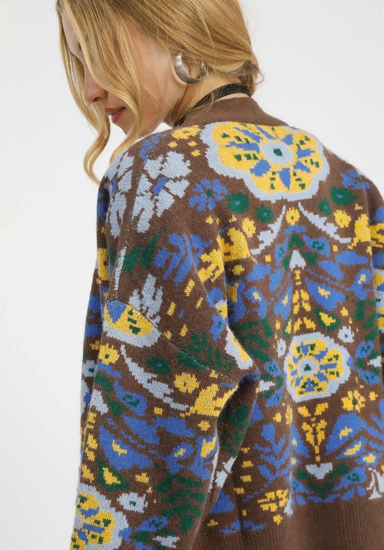 Close-up of a brown sweater with colorful geometric pattern on a white background