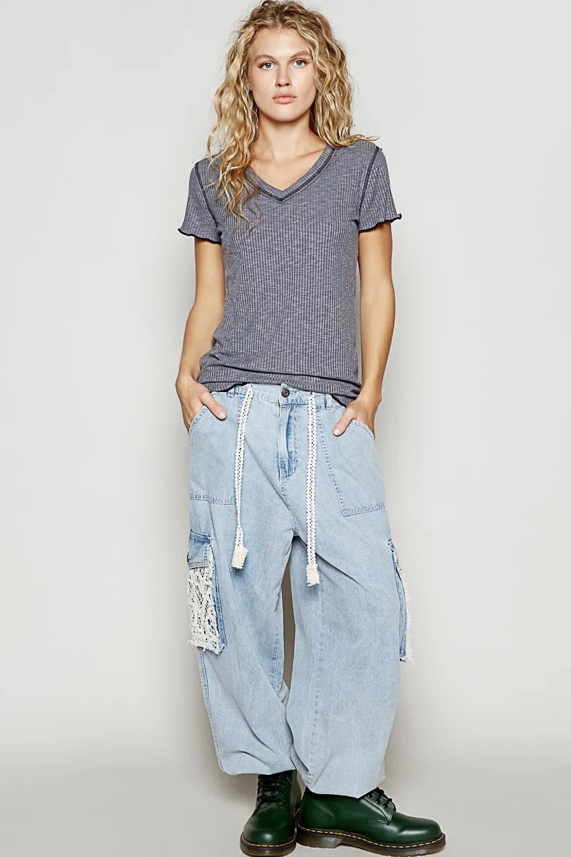 Woman wearing a gray t-shirt and light blue jeans with a white background