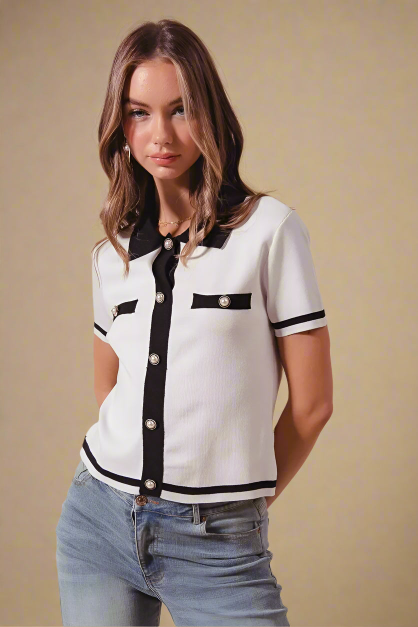Woman wearing a white and black patterned blouse with blue jeans on a beige background