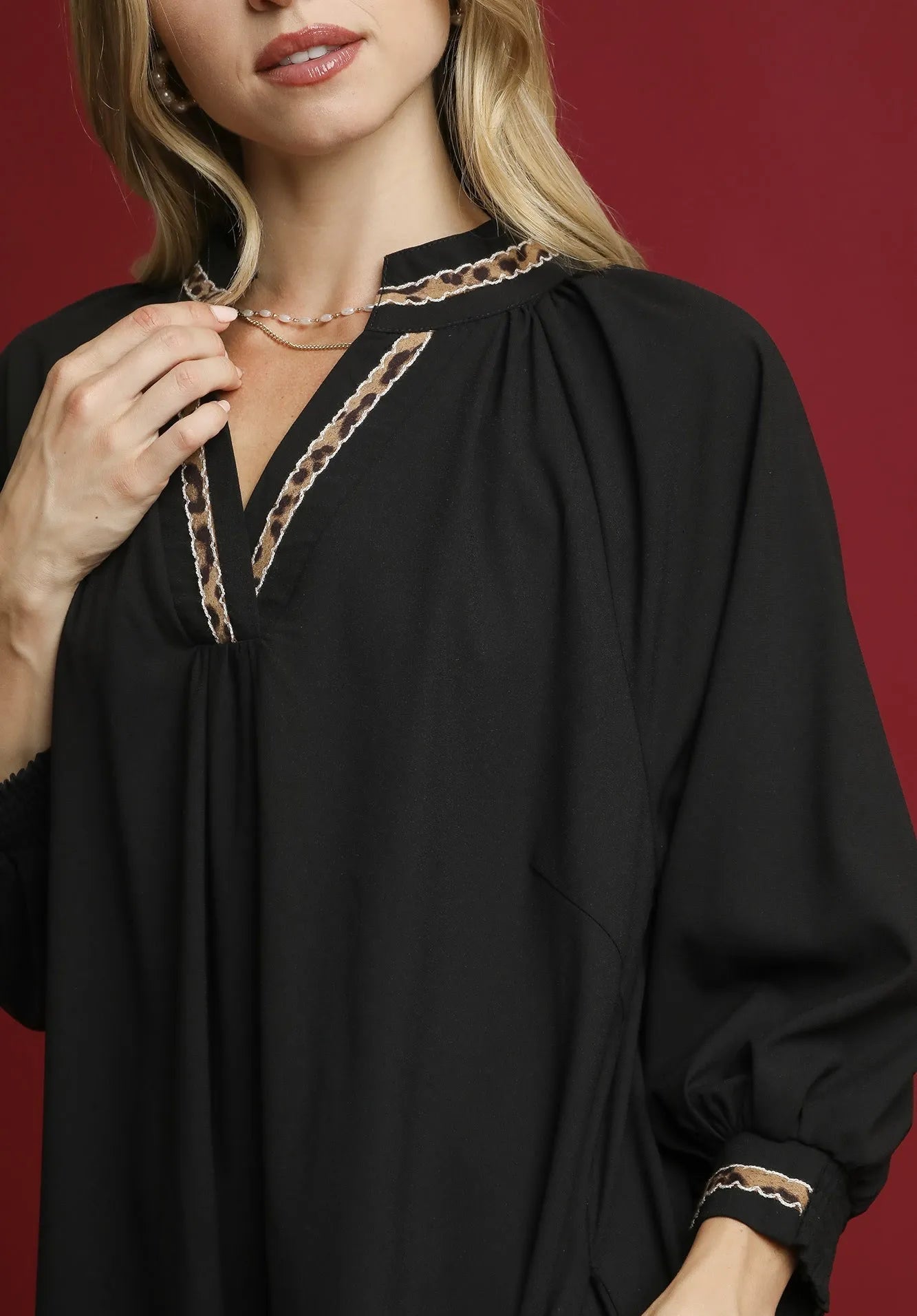 Woman wearing a black blouse with lace details on a red background