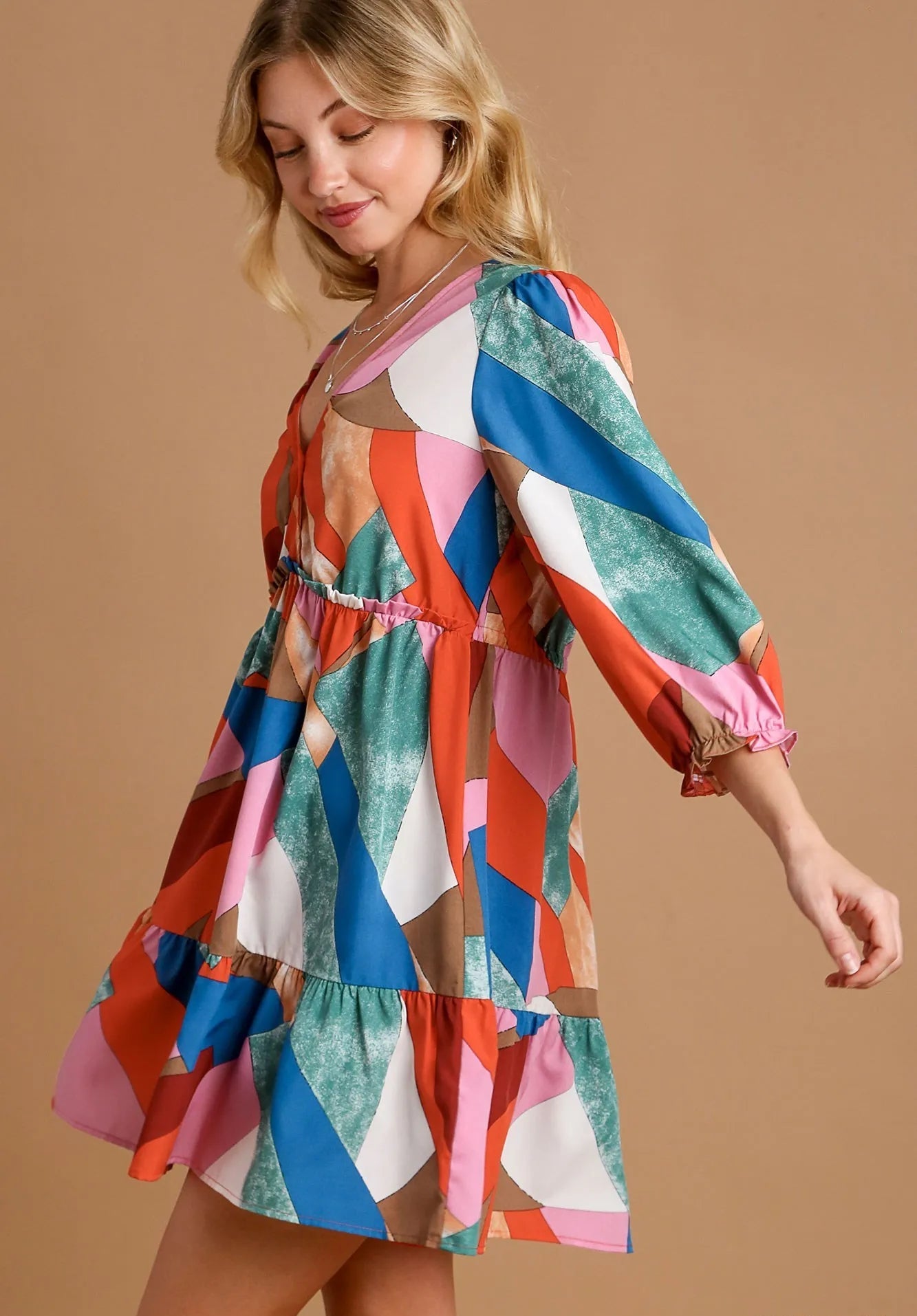 Woman wearing a colorful patterned dress on a beige background