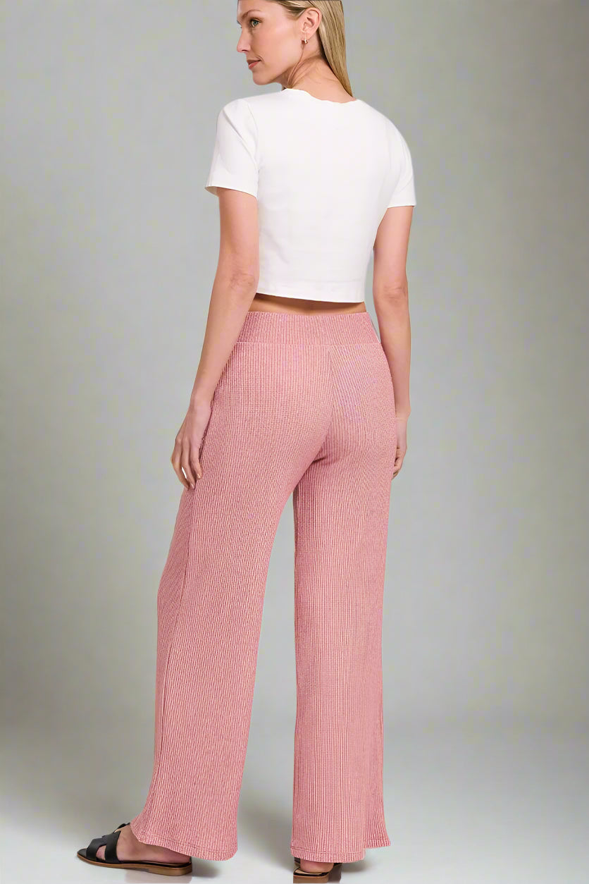 Woman wearing light rose pants and a white top on a white background