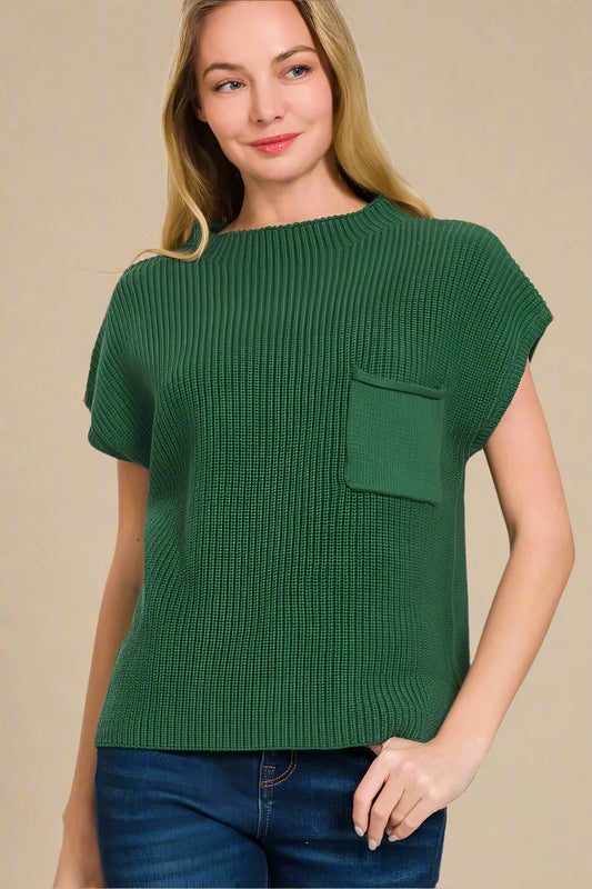 Woman wearing a green knitted top with a pocket on a beige background