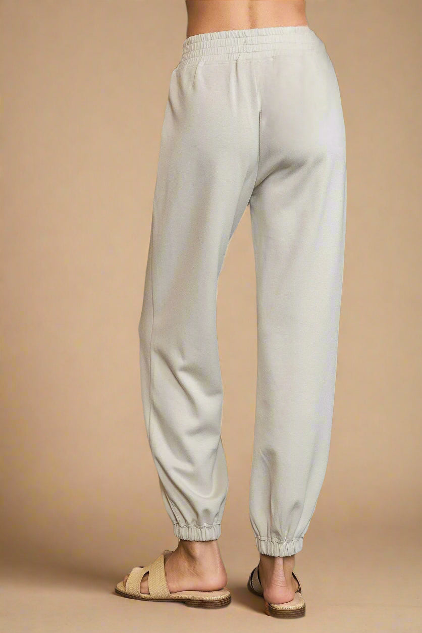 Light gray sweatpants worn by a person on a gray background