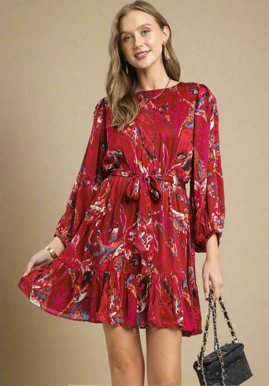 Woman wearing a red floral dress holding a black handbag on a beige background