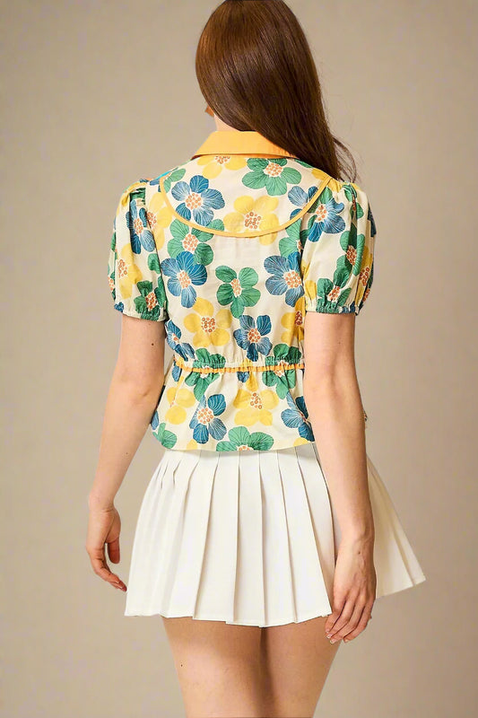 Woman wearing a floral shirt and white skirt on a plain background