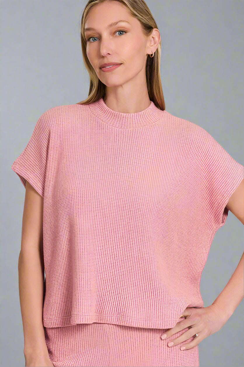 Woman wearing a light pink textured top on a white background