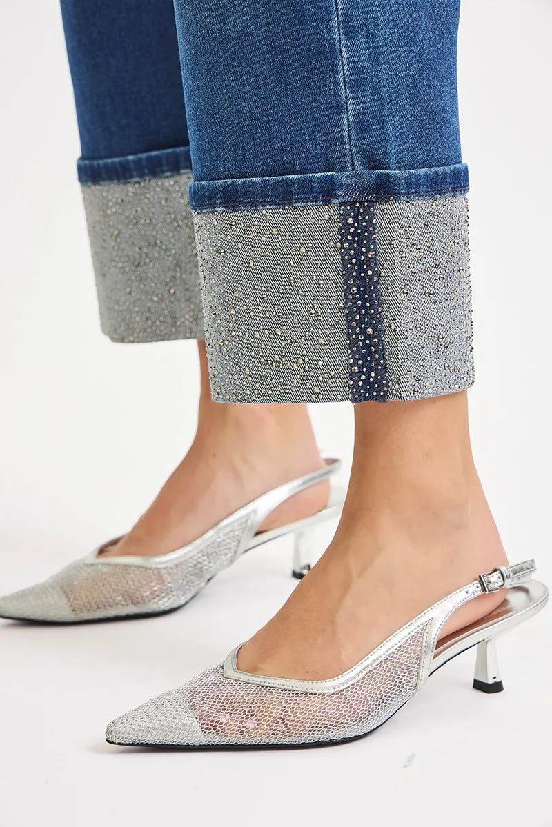 Silver high-heeled shoes worn with blue jeans featuring a glittery cuff.