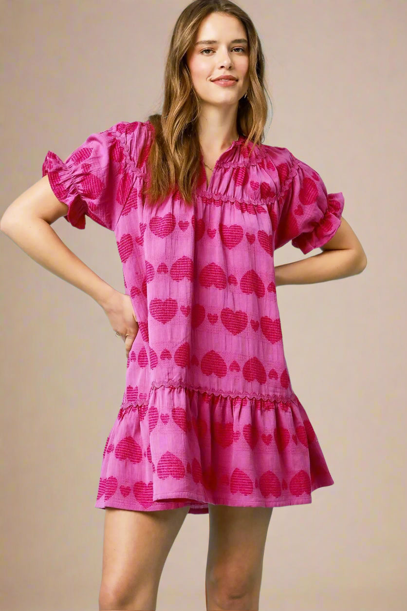 Woman wearing a pink dress with heart patterns on a beige background