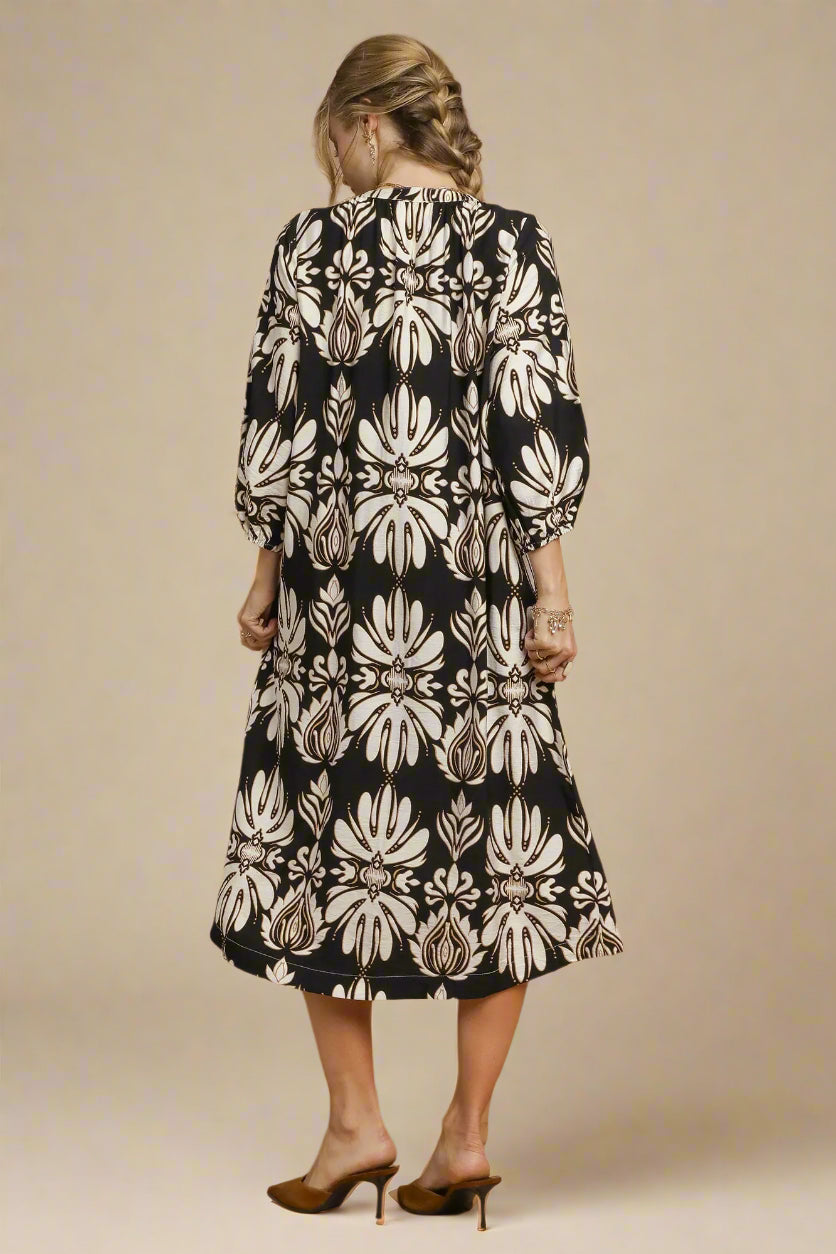 Woman wearing a black and white floral dress against a beige background
