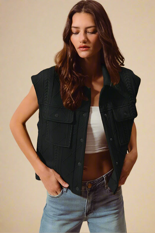 Woman wearing a black vest over a white top and blue jeans on a beige background