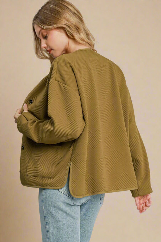 Woman wearing a camel-colored jacket on a plain background