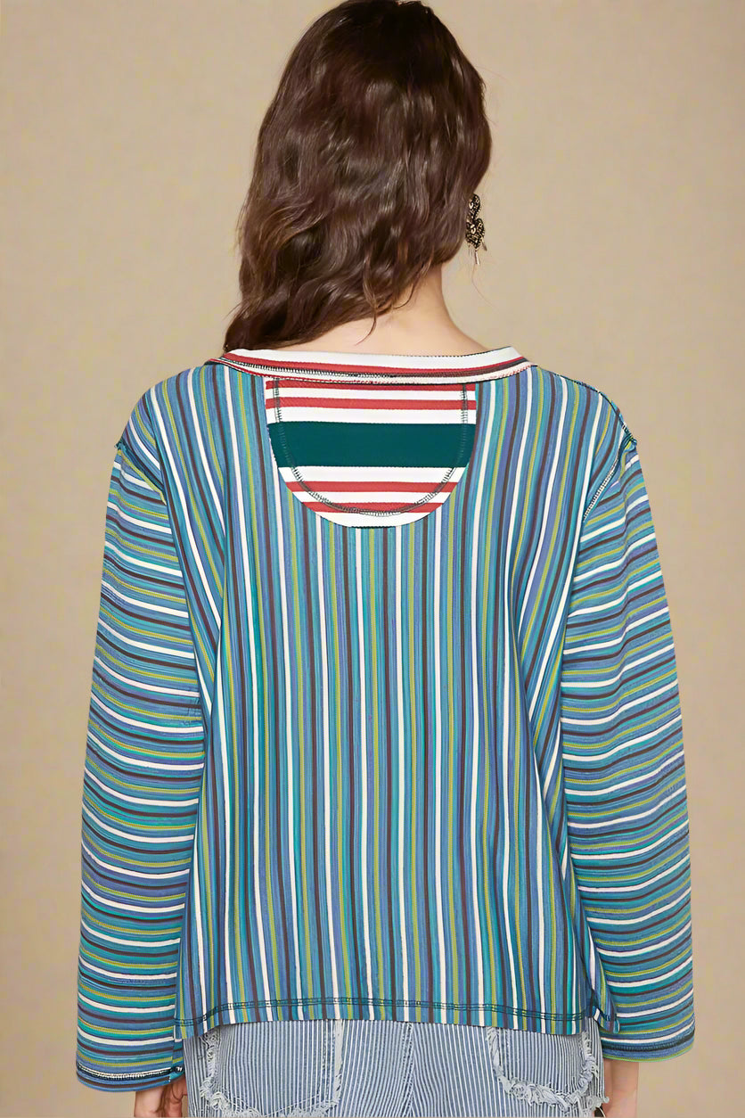 Woman wearing a colorful striped shirt with a plain background