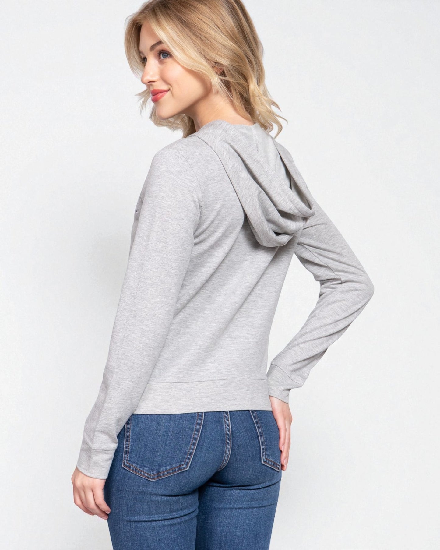 Woman wearing a gray hoodie and blue jeans on a white background