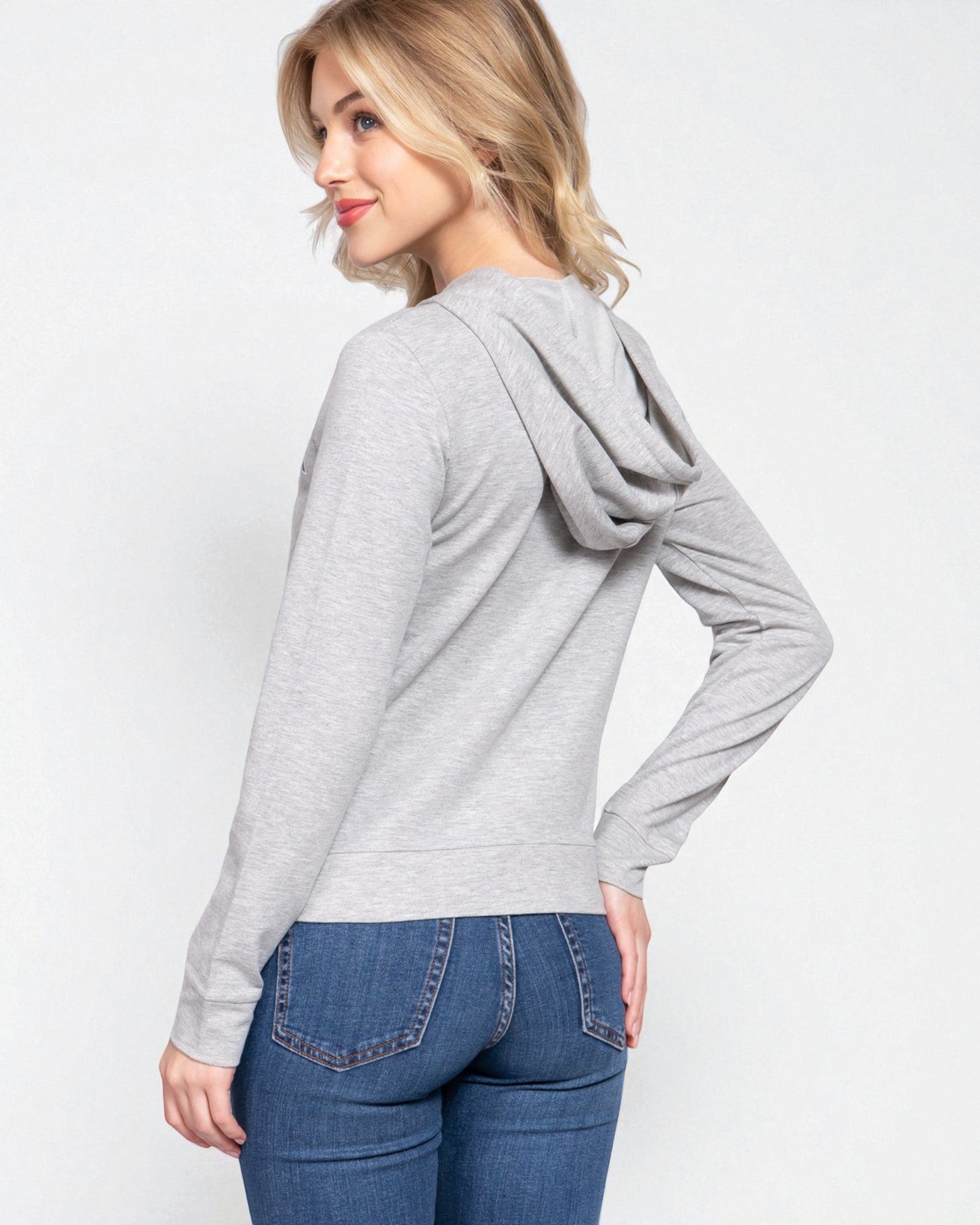 Woman wearing a gray hoodie and blue jeans on a white background