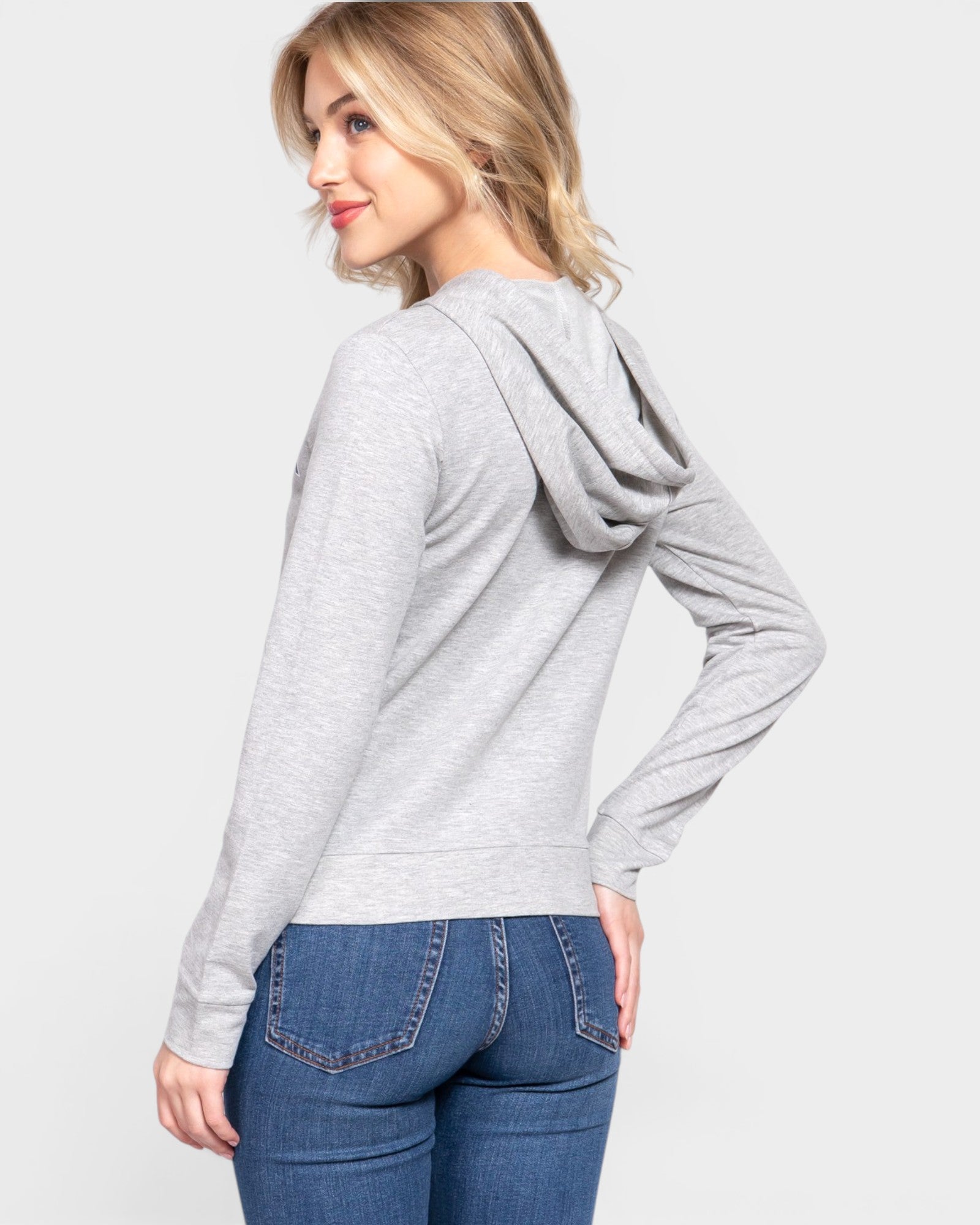Woman wearing a gray hoodie and blue jeans on a white background