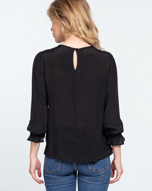 Woman wearing a black blouse with a cutout back design on a white background
