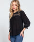 Woman wearing a black blouse with lace details on a white background