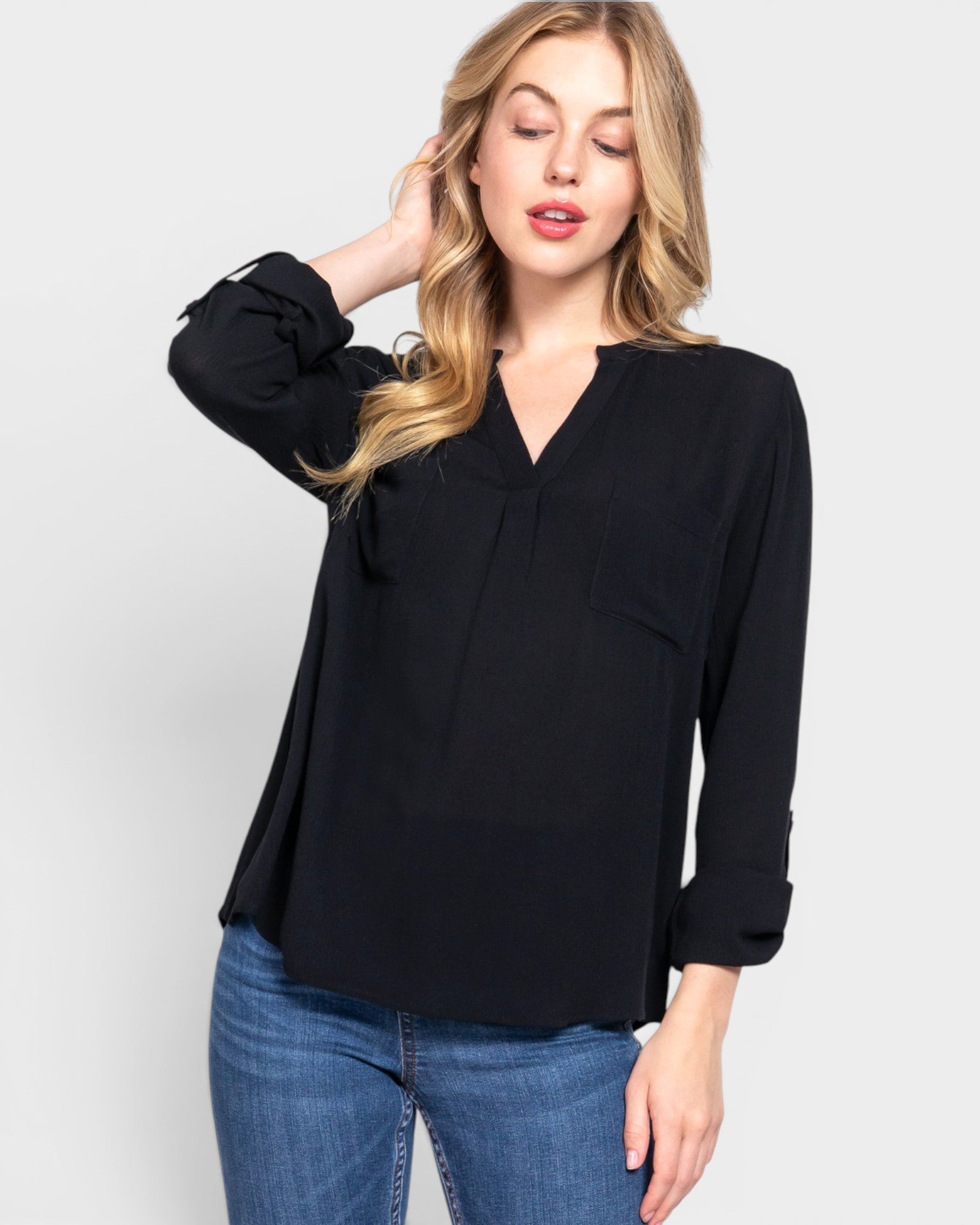 Woman wearing a black blouse and blue jeans on a white background