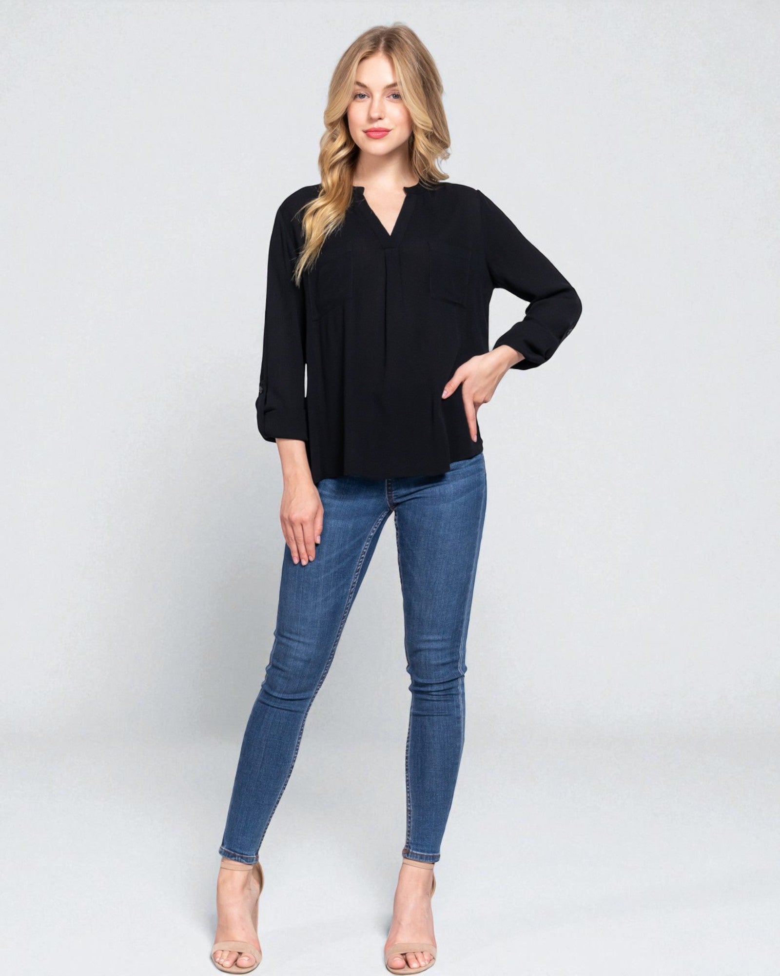 Woman wearing a black top and blue jeans on a white background