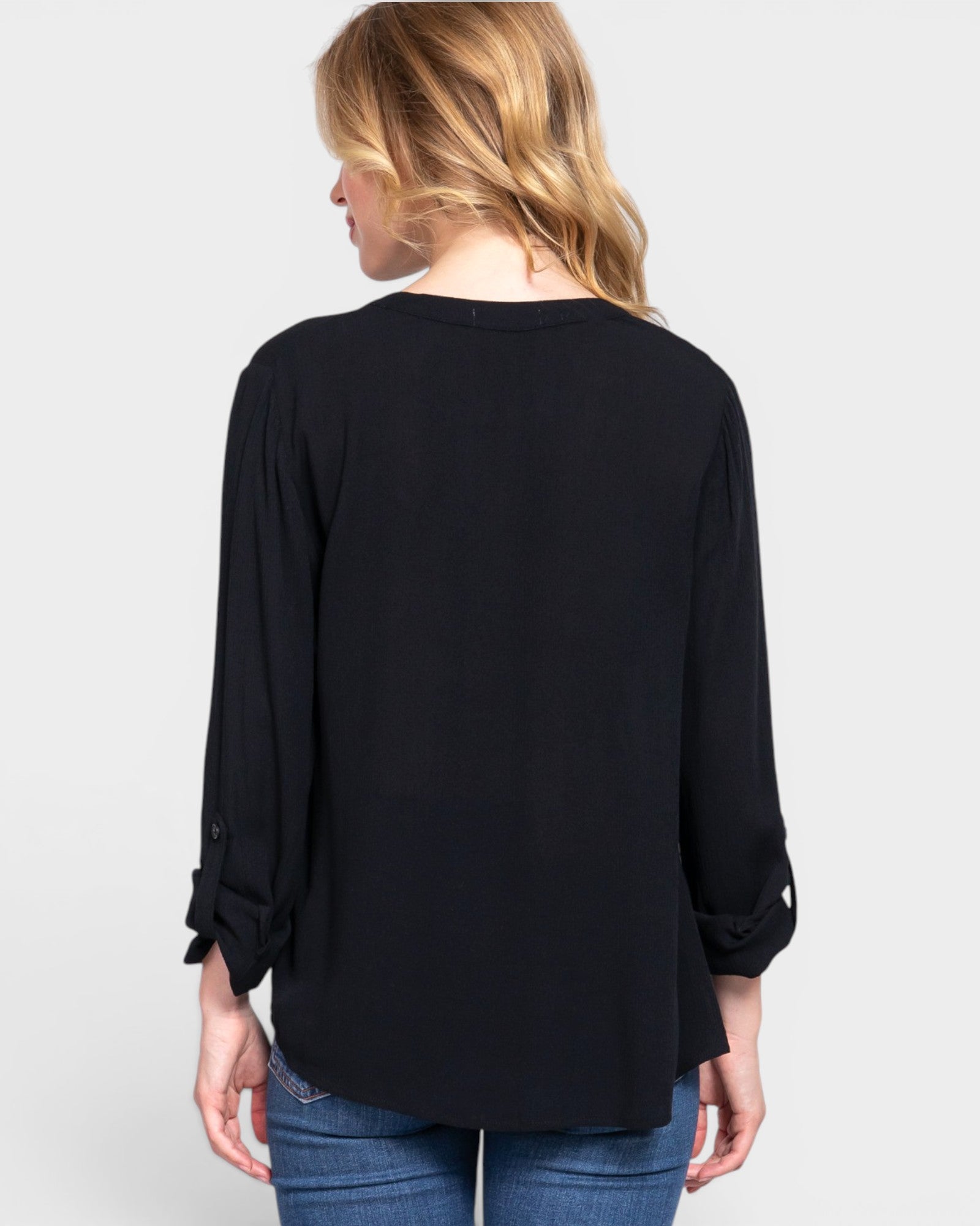 Woman wearing a black long-sleeve top on a light gray background
