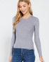 Woman wearing a gray ribbed sweater and blue jeans on a white background