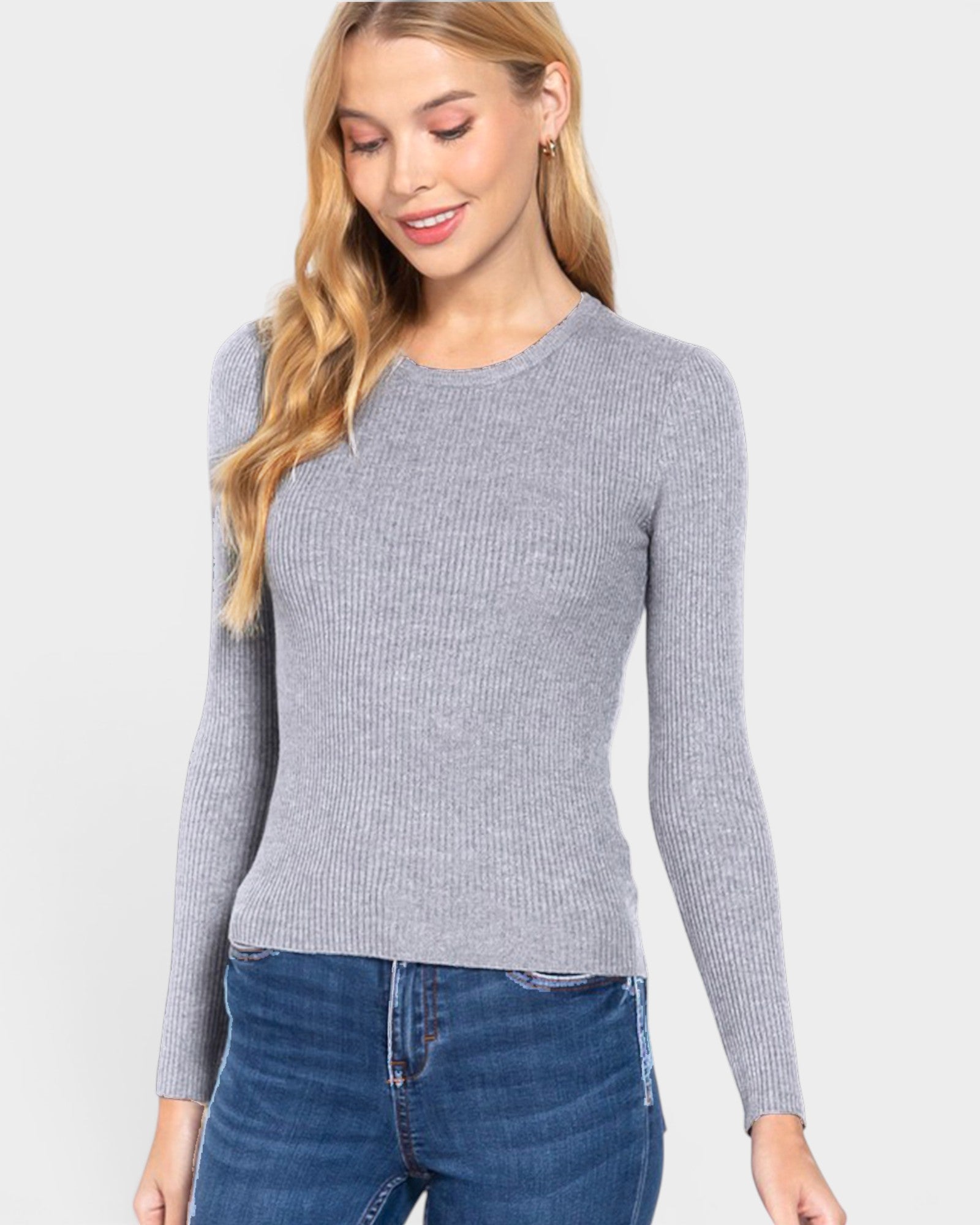 Woman wearing a gray ribbed sweater and blue jeans on a white background