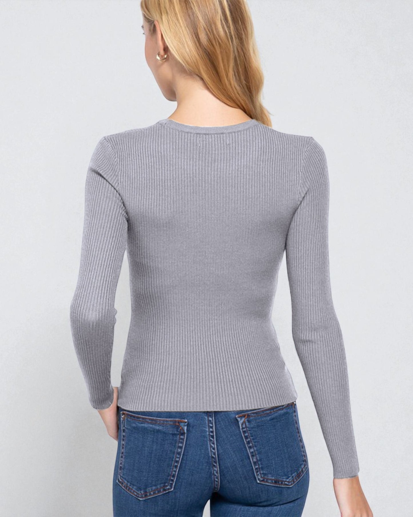 Person wearing a gray ribbed long-sleeve top and blue jeans on a light gray background