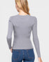 Woman wearing a gray ribbed sweater and blue jeans on a light gray background