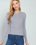 Woman wearing a gray sweater and blue jeans against a light gray background