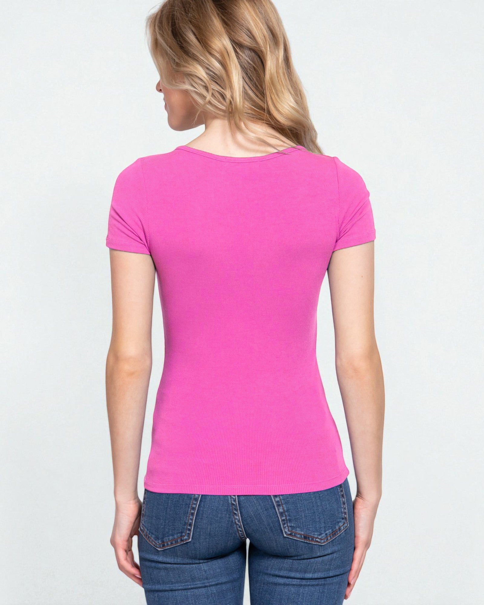 Woman wearing a pink t-shirt and blue jeans on a light gray background
