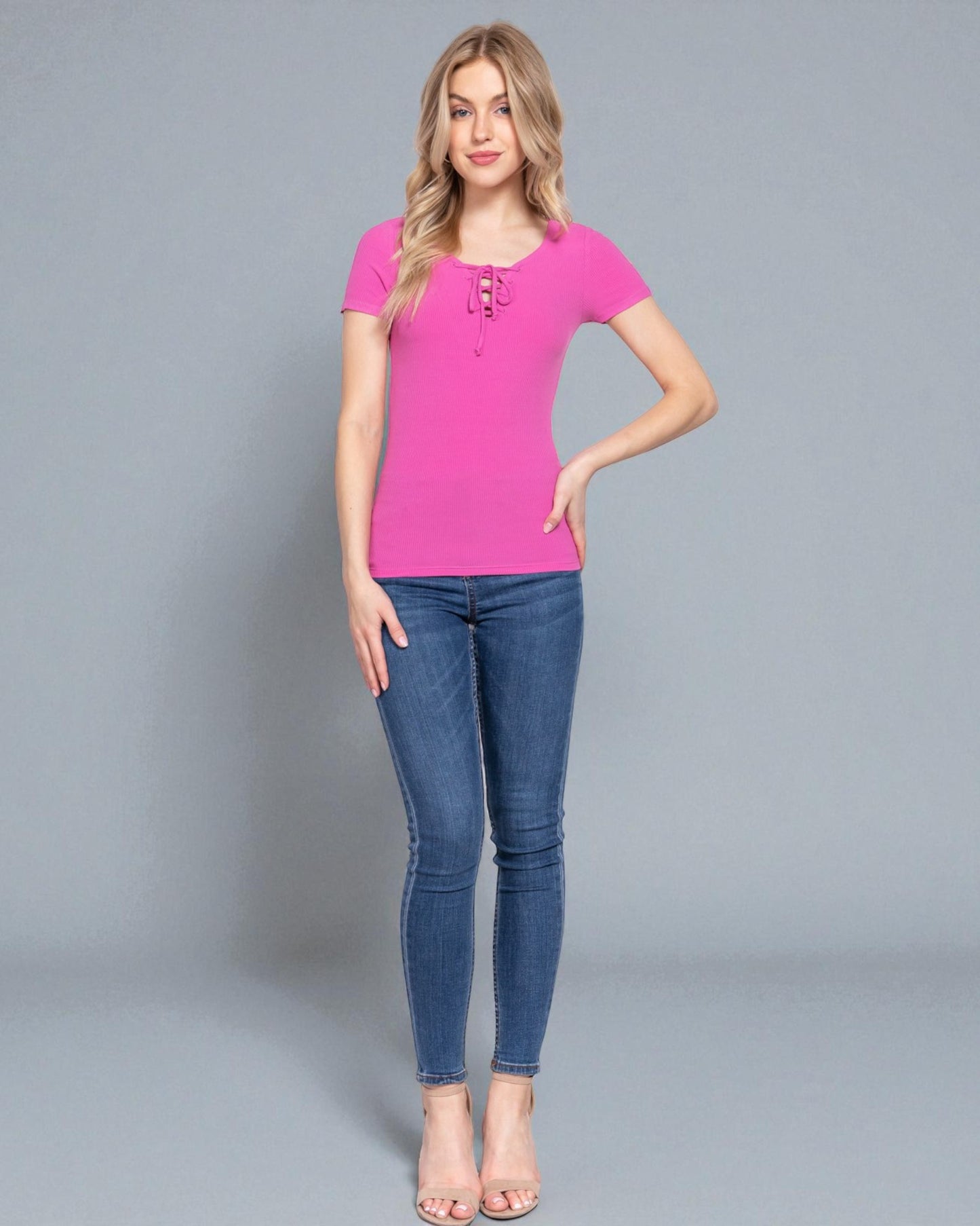 Woman wearing a pink top and blue jeans on a gray background