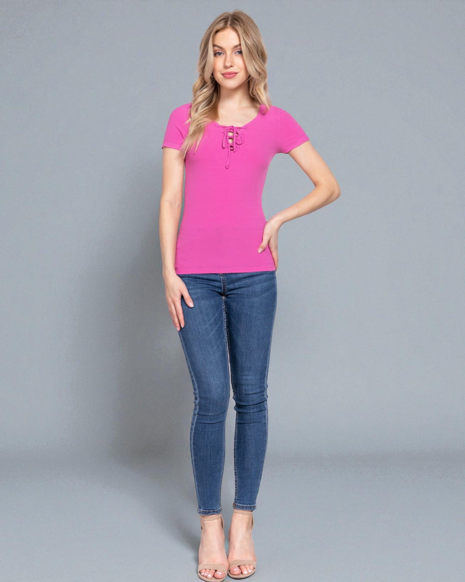 Woman wearing a pink top and blue jeans on a gray background