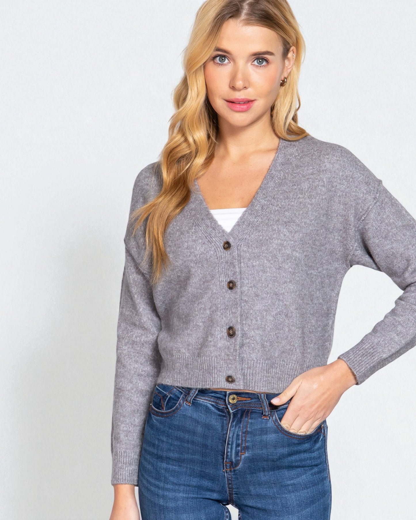 Woman wearing a gray cardigan and blue jeans on a white background