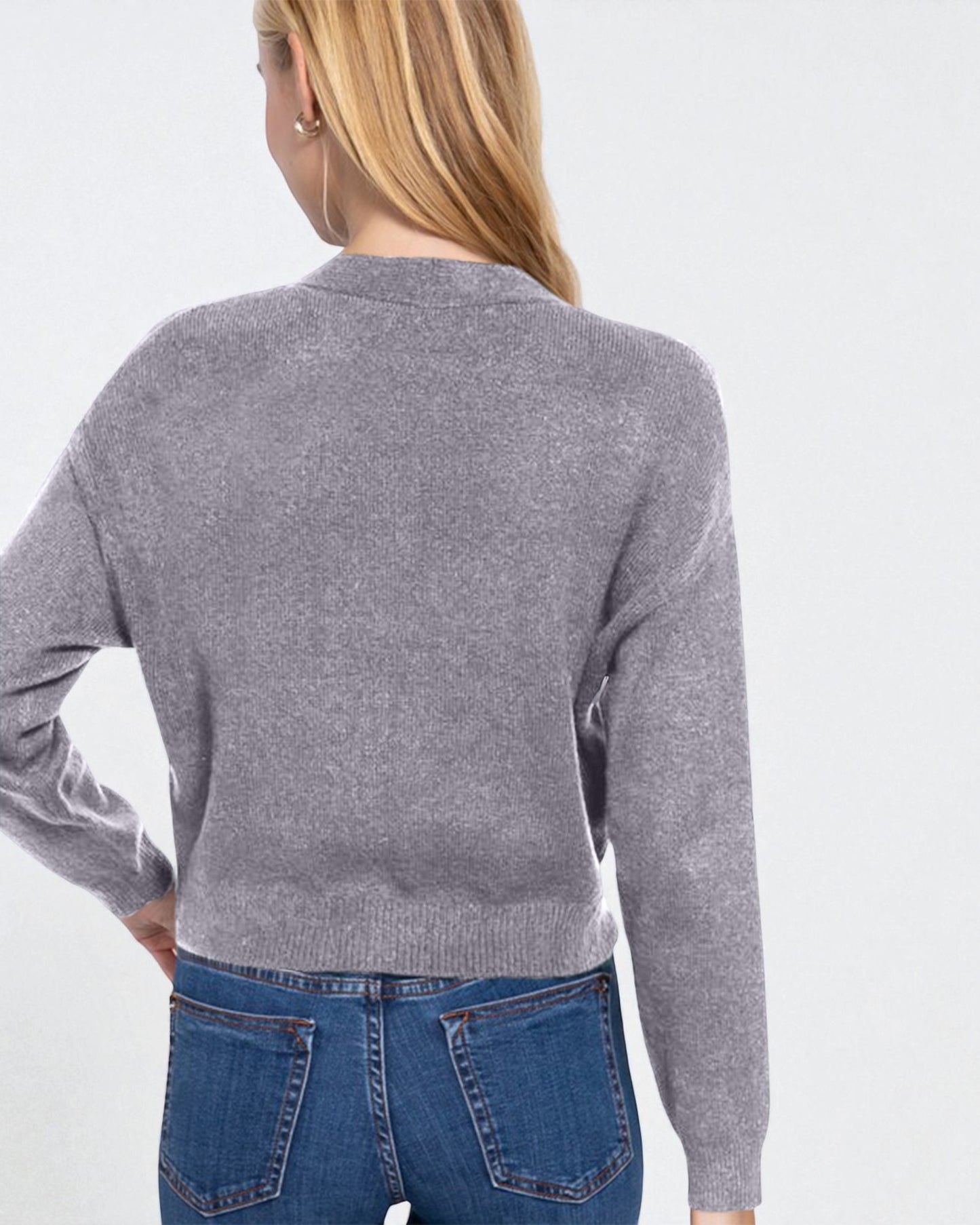 Person wearing a gray sweater and blue jeans on a white background