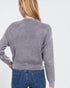 Person wearing a gray sweater and blue jeans on a white background
