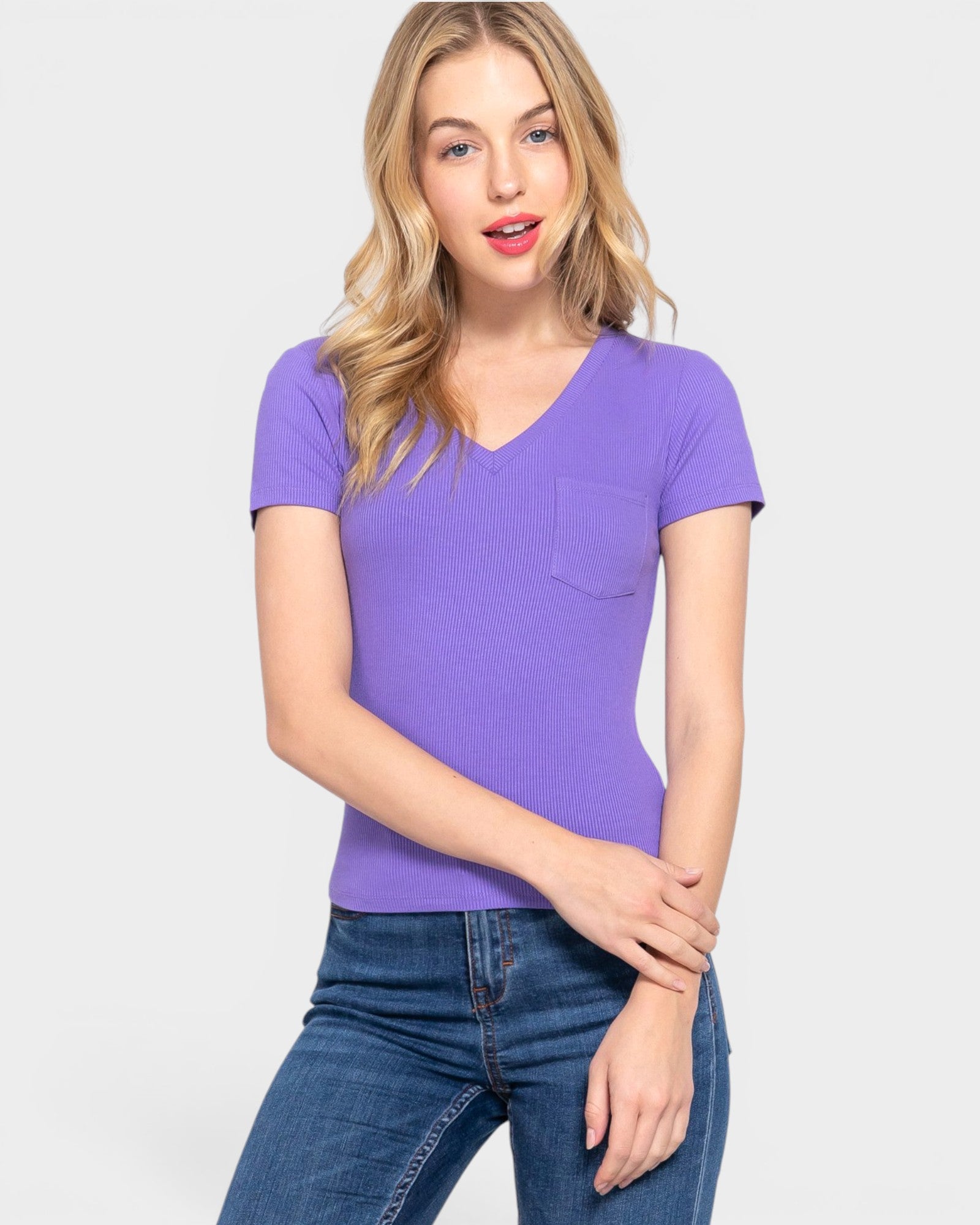 Woman wearing a purple V-neck t-shirt with a pocket on a light gray background