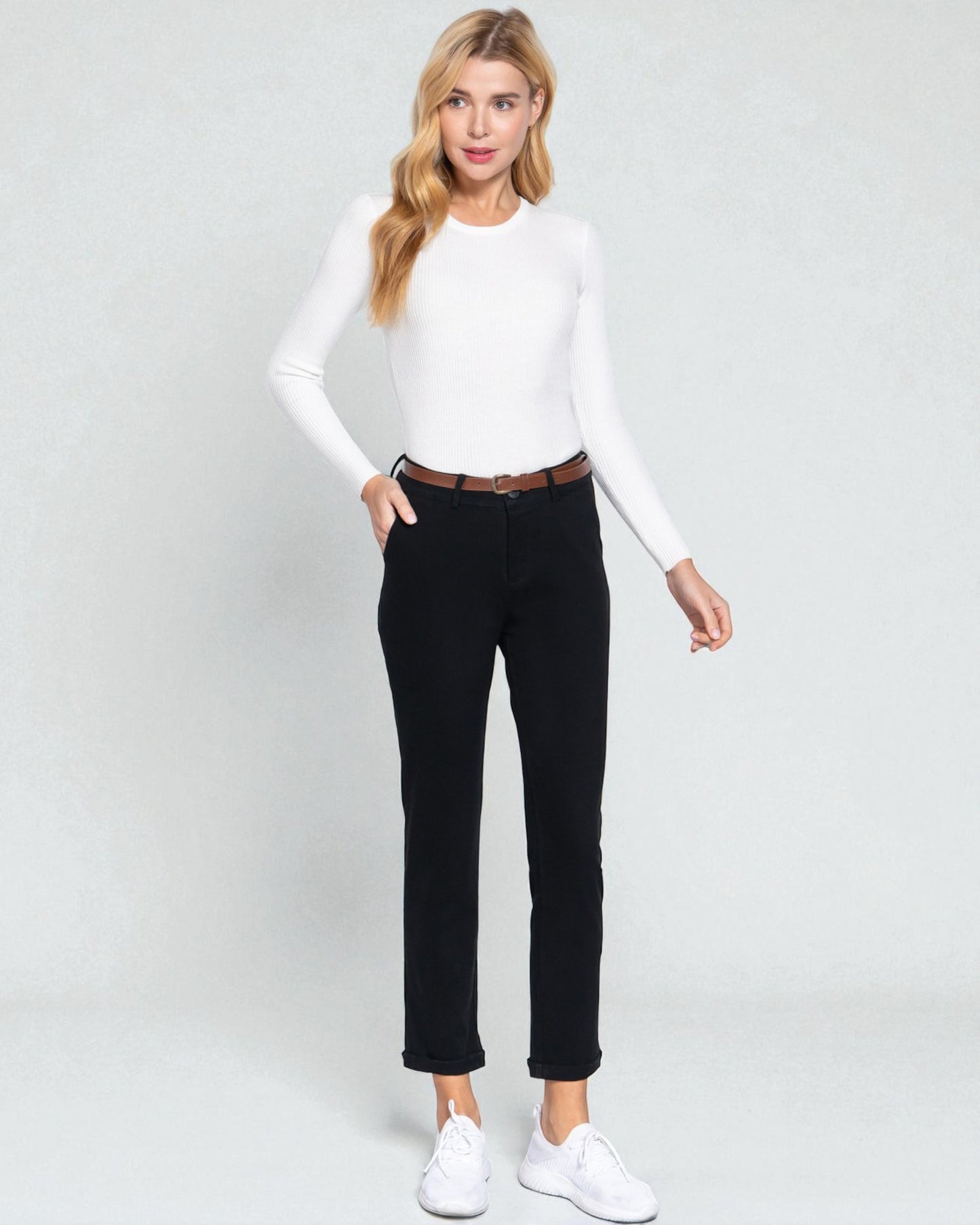 Woman wearing a white long-sleeve top and black pants on a white background