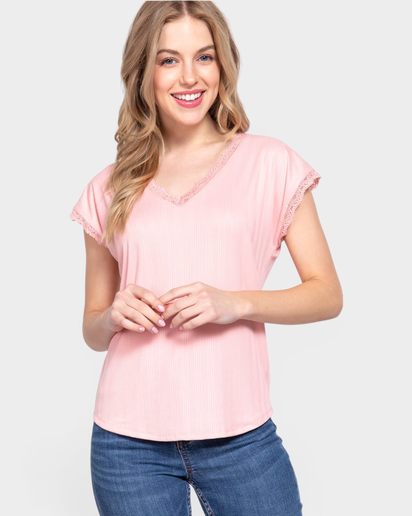 Woman wearing a pink top and blue jeans on a white background