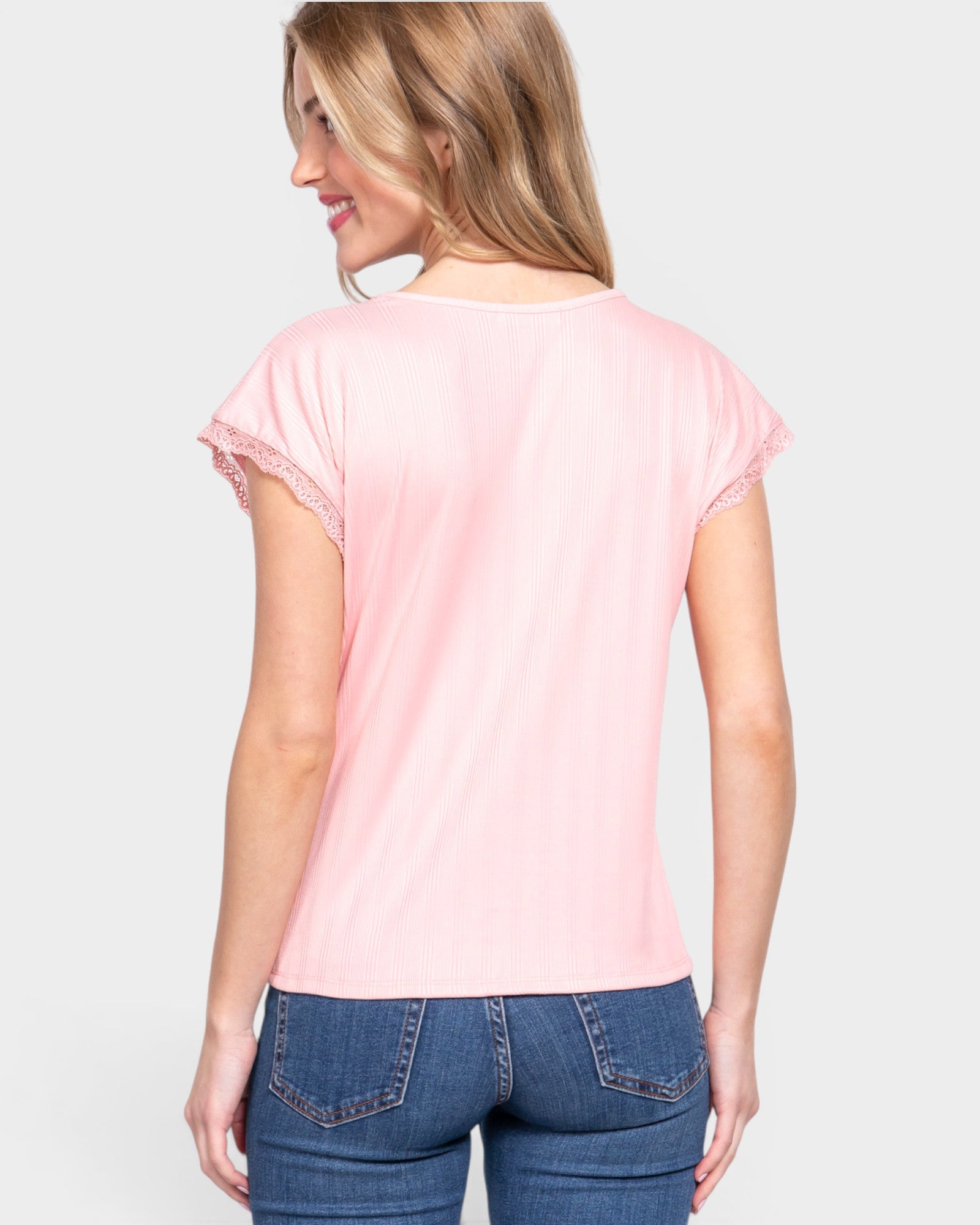 Woman wearing a pink t-shirt and blue jeans on a white background