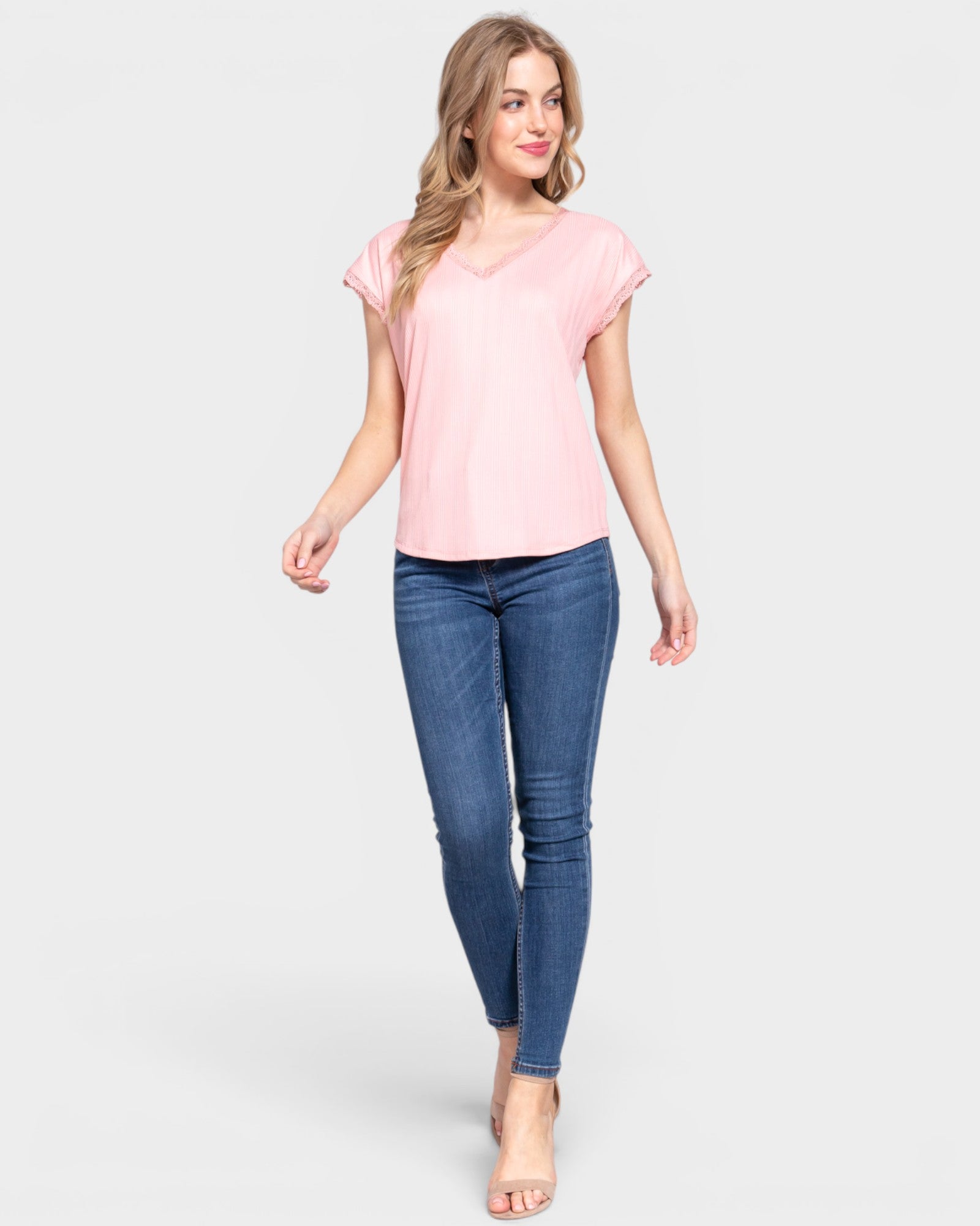 Woman wearing a pink top and blue jeans on a white background