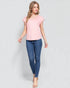 Woman wearing a pink top and blue jeans on a light gray background