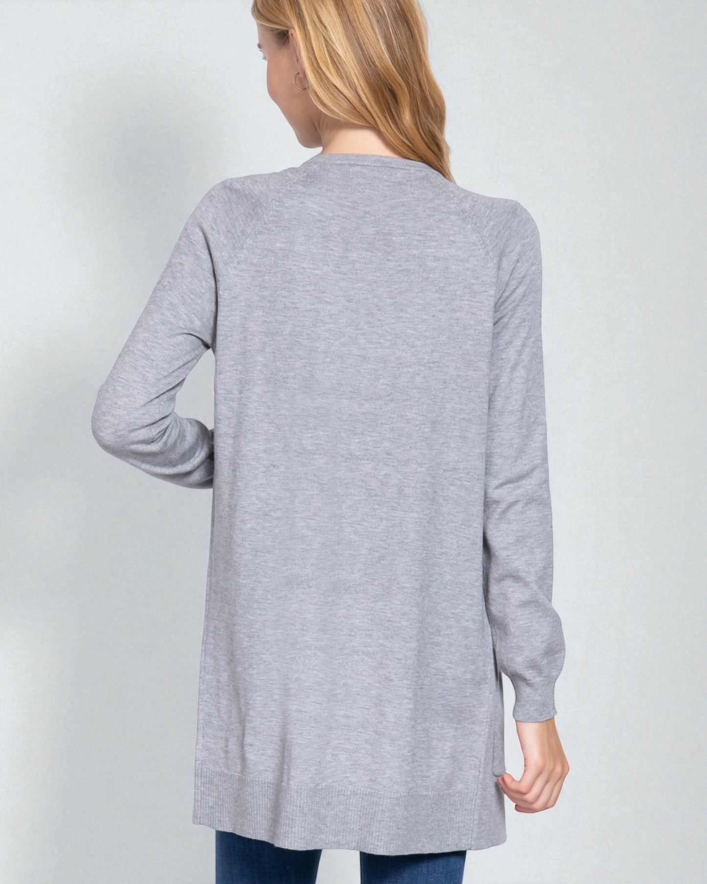 Person wearing a gray cardigan on a plain background