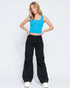 Woman wearing a blue crop top and black pants on a white background