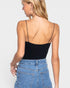 Woman wearing a black bodysuit and blue jeans against a white background
